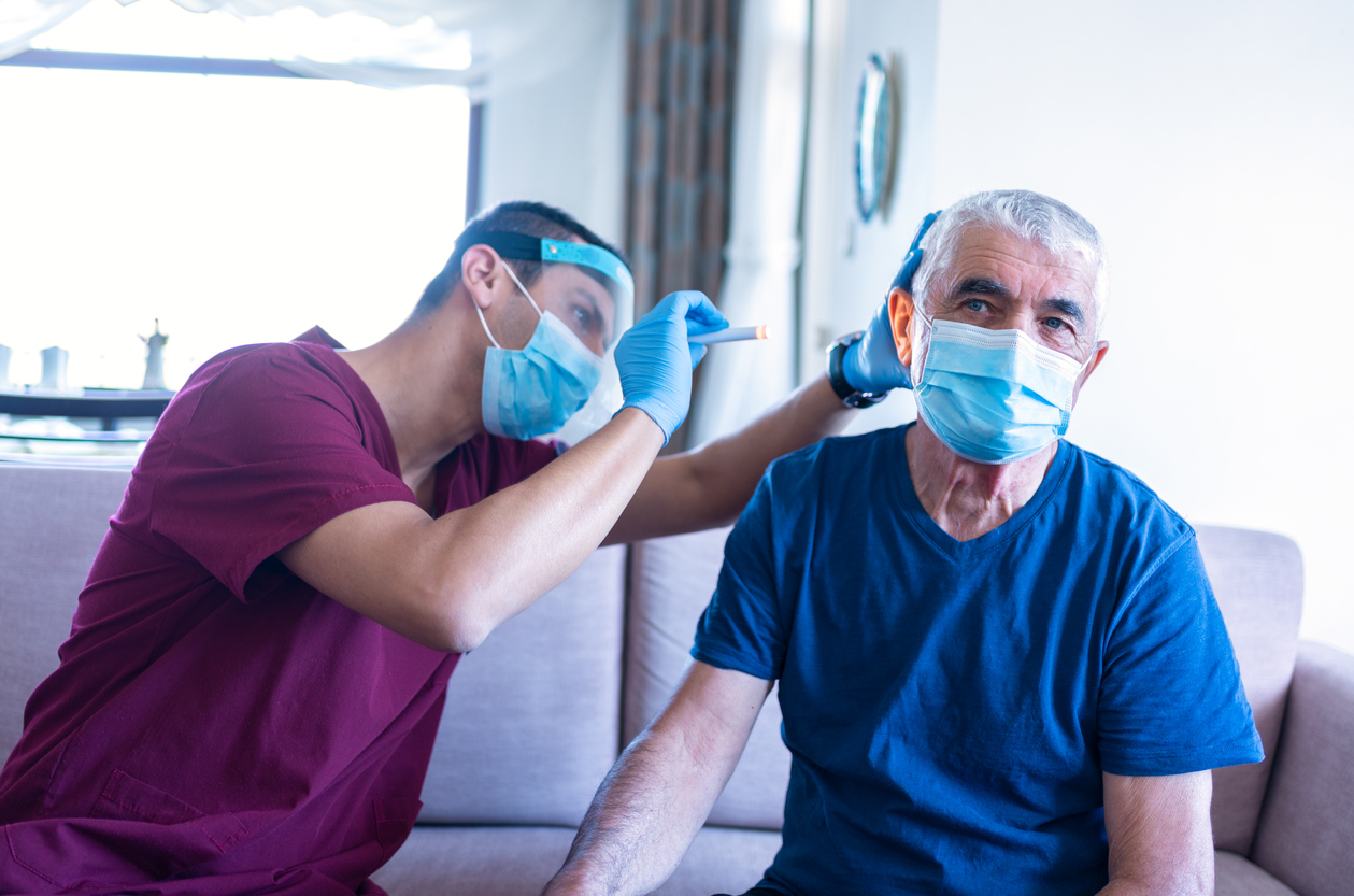 A male doctor diagnosing and treating a male patient with Tinnitus in his home.